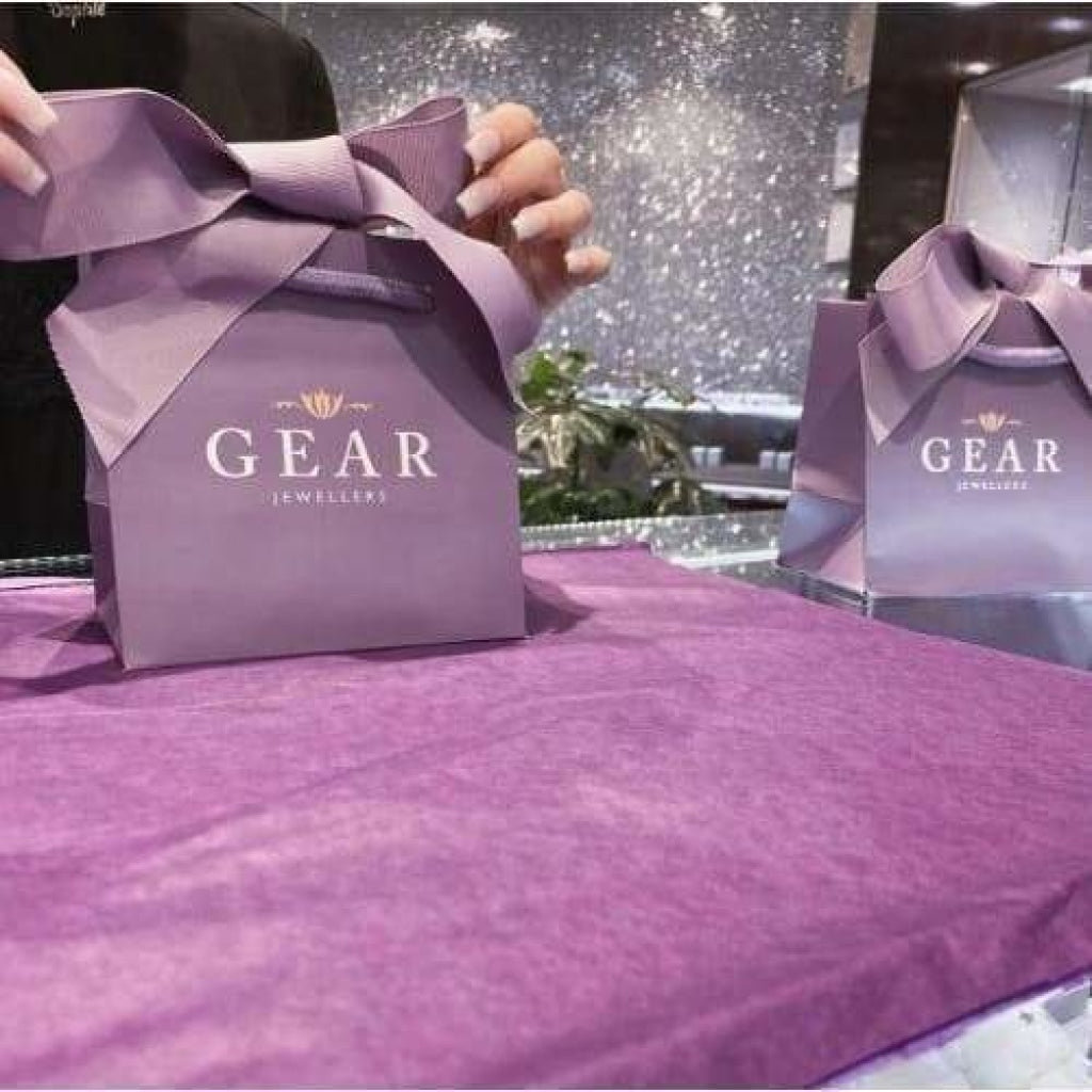 A woman tying a bow in a purple Gear Jewellers gift bag.