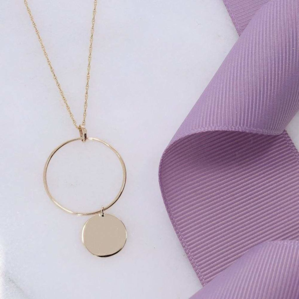9ct circle & disc necklace beside a purple ribbon